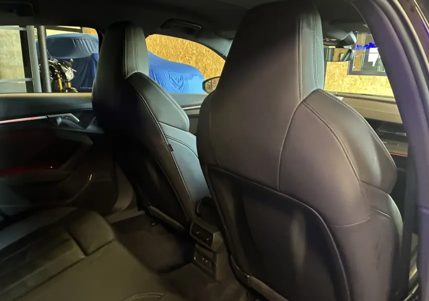Vue intérieure arrière de l'Audi A3 Sportback noire 2022, mettant en valeur les sièges avant en cuir noir et l'ambiance raffinée.