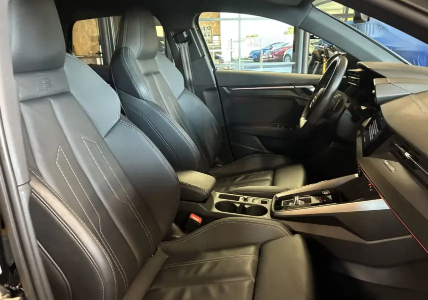 Vue intérieure côté gauche de l'Audi A3 Sportback 2022 avec sièges en cuir noir et tableau de bord moderne.