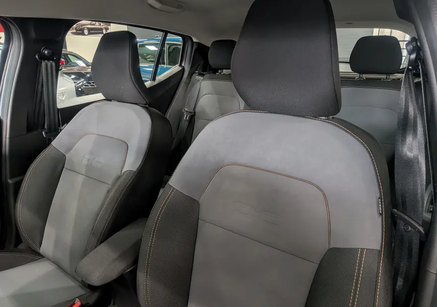 Vue intérieure rapprochée des sièges avant en tissu gris et noir avec surpiqûres orange du Dacia Sandero Stepway 2025.