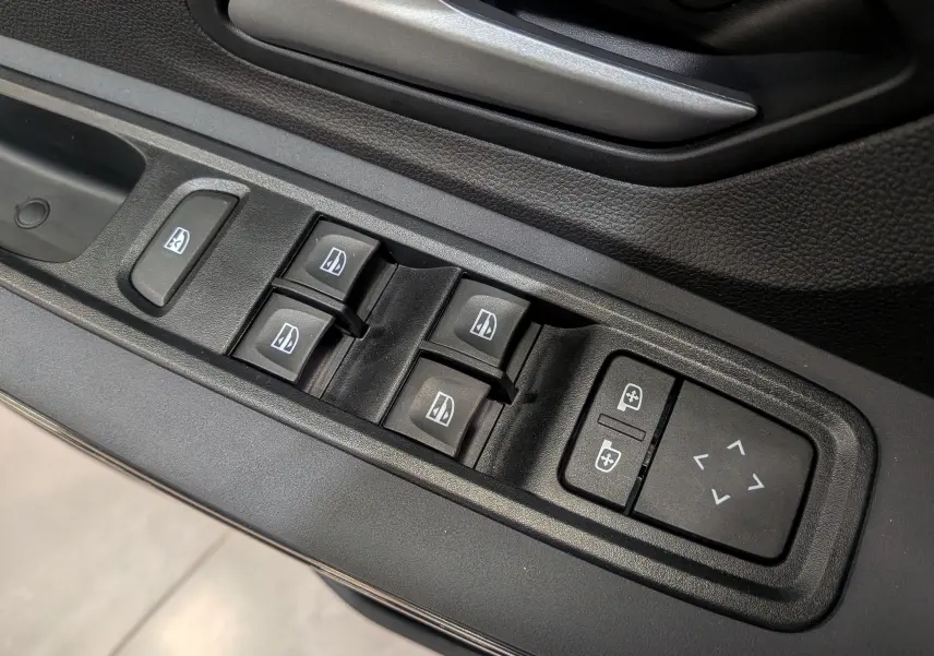 Gros plan sur les commandes de lève-vitres et réglage des rétroviseurs côté conducteur d'une Dacia Sandero Stepway 2025.