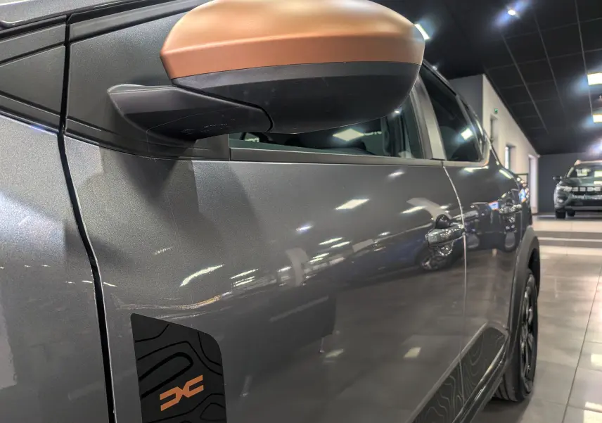 Gros plan sur le rétroviseur cuivré et la portière gris schiste côté gauche de la Dacia Sandero Stepway TCe 110 CH Extreme 2025.
