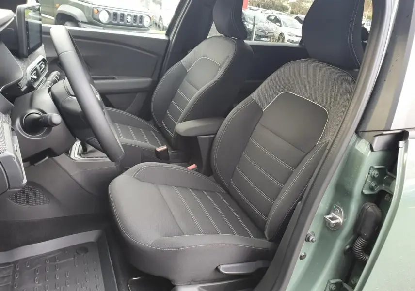 Vue intérieure côté conducteur du Dacia Jogger 2024 en Licken Kaki, montrant les sièges avant noirs avec accoudoir.