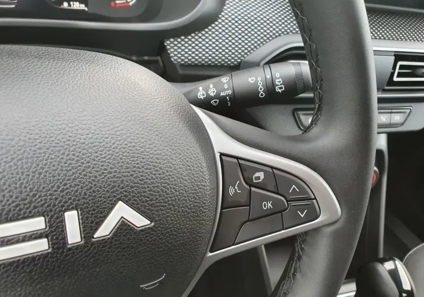 Gros plan sur le volant cuir noir du Dacia Jogger 2024 avec commandes multifonctions et tableau de bord partiel.