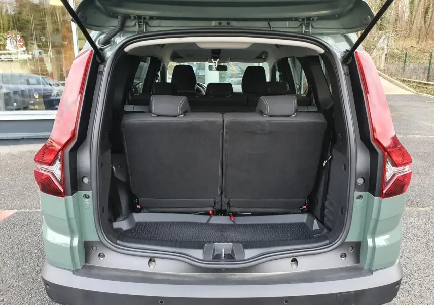 Vue arrière du Dacia Jogger 2024 en Licken Kaki, coffre ouvert montrant la banquette arrière noire et les feux arrière rouges.