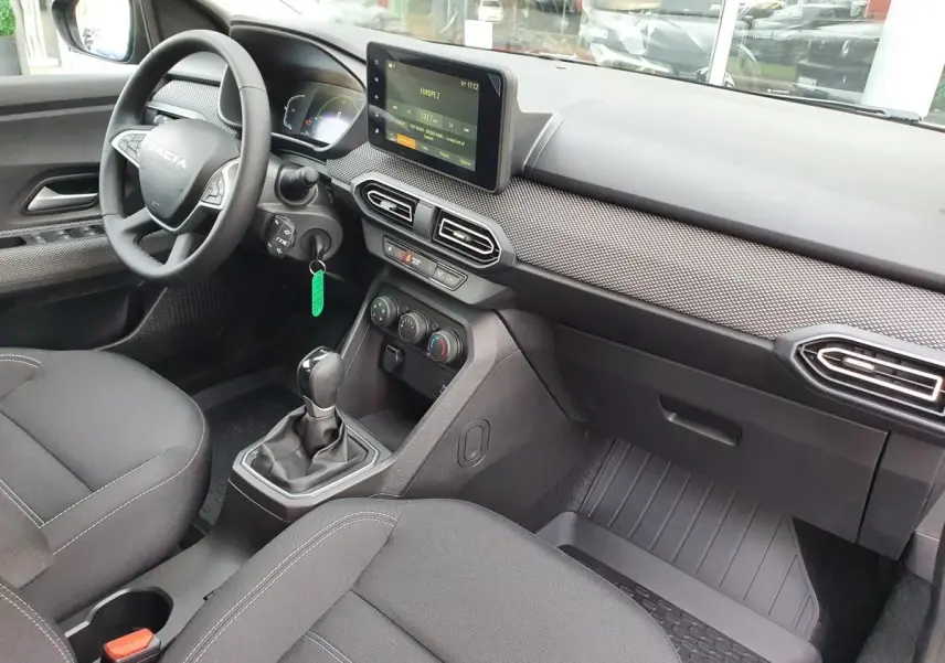 Vue intérieure côté conducteur du Dacia Jogger 2024, tableau de bord avec écran tactile et volant multifonction noir.