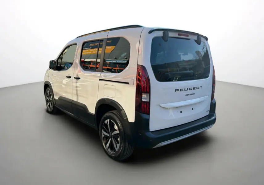 Vue 3/4 arrière droite du Peugeot Rifter blanc kaolin avec barres de toit et jantes alu noires.