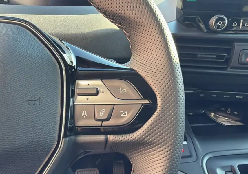 Gros plan sur le volant cuir perforé du Peugeot Rifter 2025, avec commandes multifonctions intégrées.