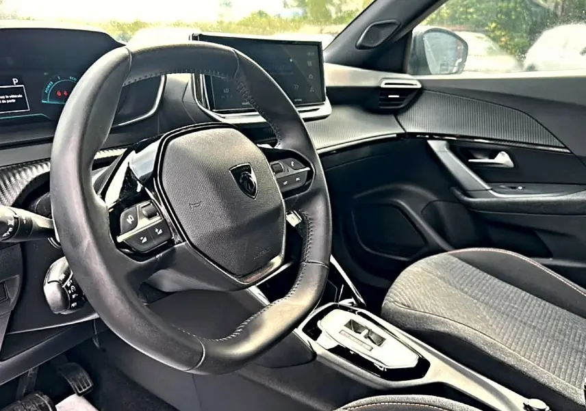 Intérieur du Peugeot 2008 hybride 2025, vue côté conducteur, volant multifonction et tableau de bord numérique.