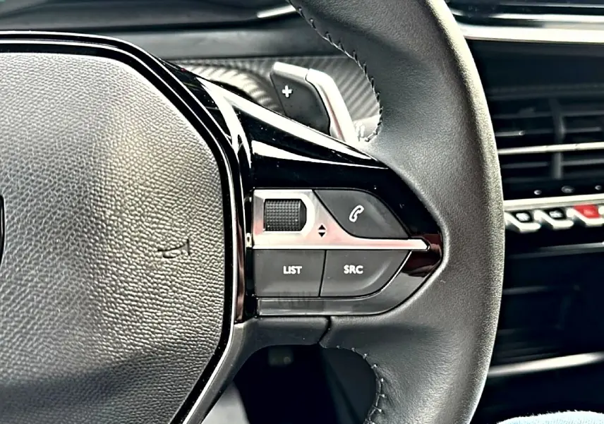 Gros plan sur la partie droite du volant noir du Peugeot 2008 gris, avec commandes audio et téléphone intégrées.