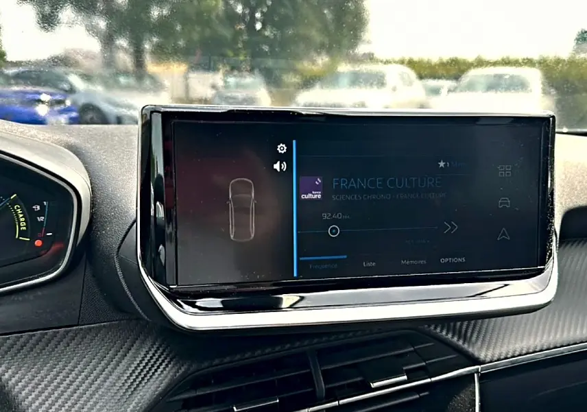 Écran tactile central allumé dans l’habitacle d’une Peugeot 2008 gris, vue de face côté conducteur.