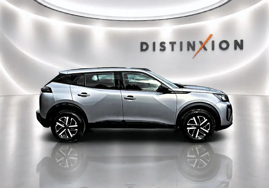 Peugeot 2008 gris en profil droit dans un studio lumineux avec logo Distinxion en arrière-plan.
