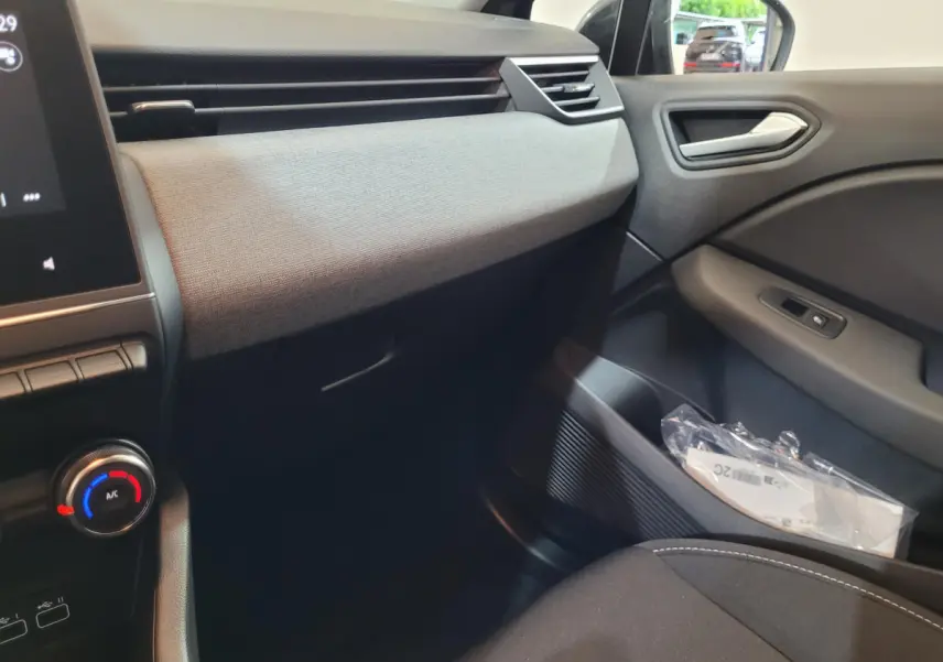 Vue intérieure côté passager de la Renault Clio gris foncé 2025, avec tableau de bord et portière en tissu gris.