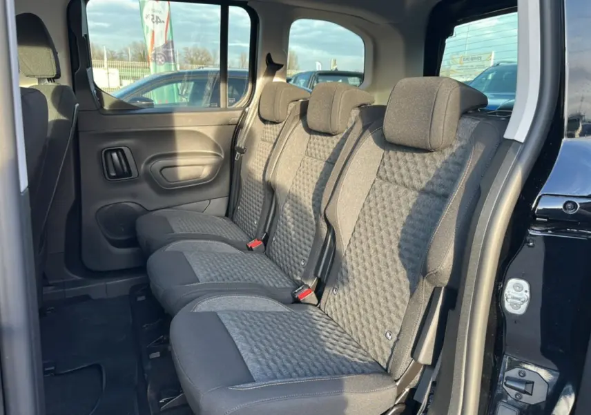 Vue intérieure côté droit des sièges arrière en tissu gris du Peugeot Rifter Noir Perla Nera avec porte coulissante ouverte.