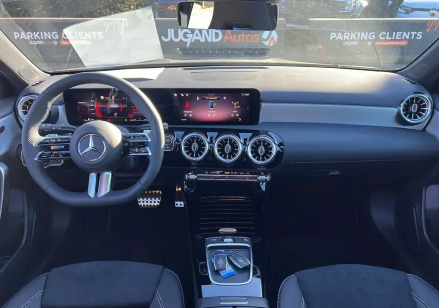 Vue intérieure avant de la Mercedes Classe A 200D Exclusive Design noire, avec tableau de bord numérique et volant multifonctions cuir.