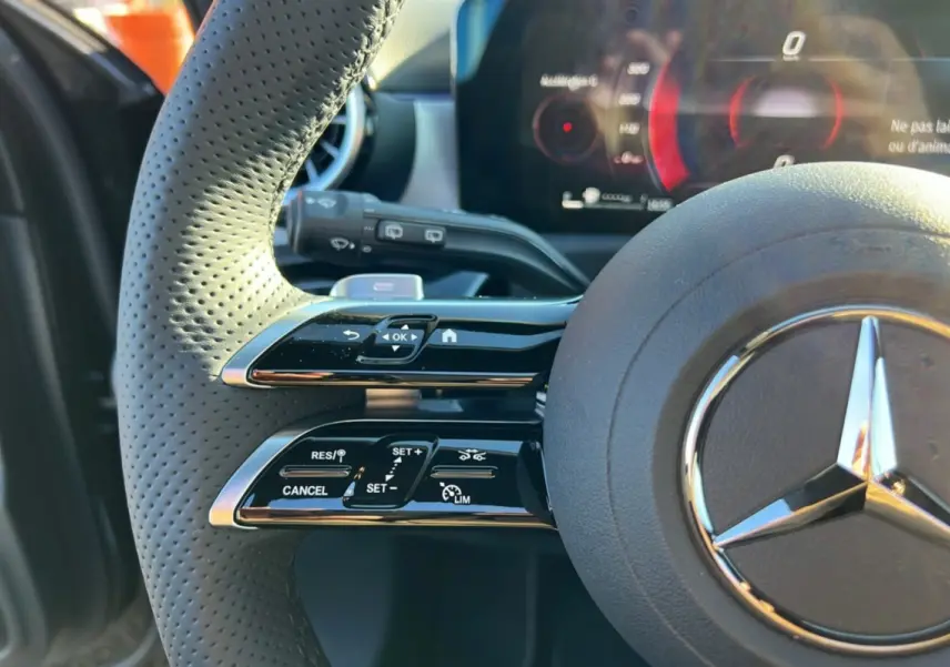 Gros plan sur le volant cuir multifonctions noir de la Mercedes Classe A 200D BVA Exclusive Design avec commandes intégrées.