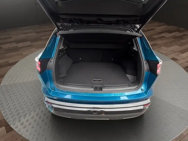 Vue arrière du Renault Austral bleu 2026 avec hayon motorisé ouvert, montrant le coffre spacieux et l'éclairage arrière LED.