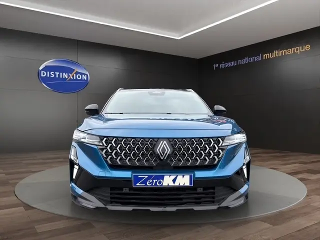 Vue frontale du Renault Austral bleu bi-ton avec calandre distinctive et hayon motorisé visible en arrière-plan.