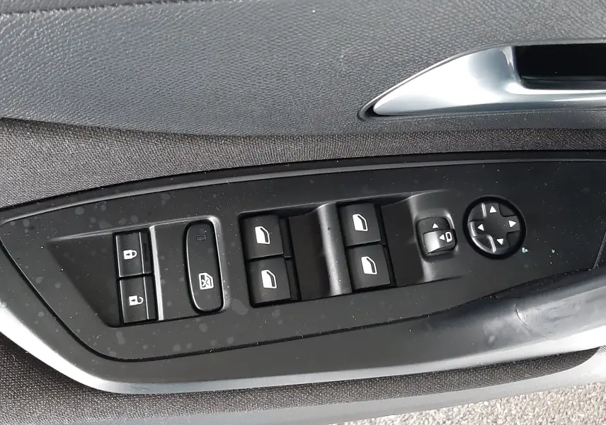 Gros plan sur les commandes de lève-vitres et rétroviseurs côté conducteur d'une Peugeot 308 blanche de 2022.