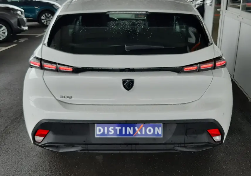 Vue arrière d'une Peugeot 308 blanche banquise 2022 avec feux LED et logo lion noir sur le hayon.
