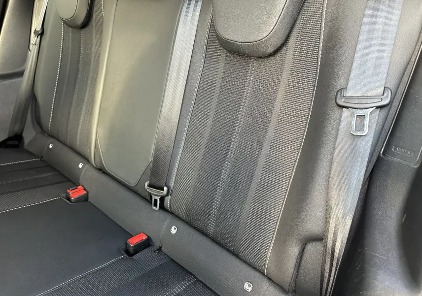 Vue rapprochée des sièges arrière noirs en tissu et cuir du Opel Mokka Elegance 2021 avec ceintures de sécurité visibles.