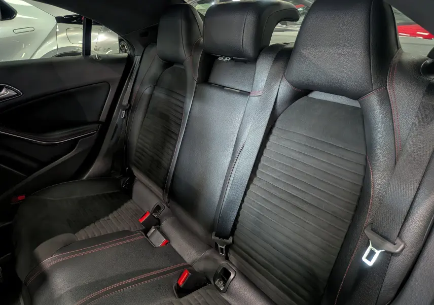 Vue intérieure des sièges arrière en cuir noir avec surpiqûres rouges d'une Mercedes CLA 200 Fascination 2017.
