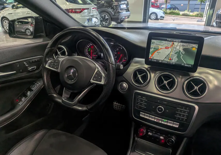 Intérieur de la Mercedes Classe CLA 200 7G-Tronic 2017, vue du poste de conduite avec écran GPS et volant cuir noir.