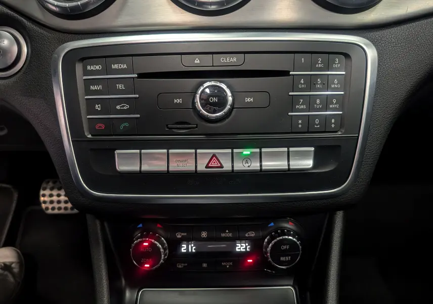 Vue rapprochée du tableau de bord central d'une Mercedes Classe CLA 200 Fascination, avec commandes multimédia et climatisation digitale.