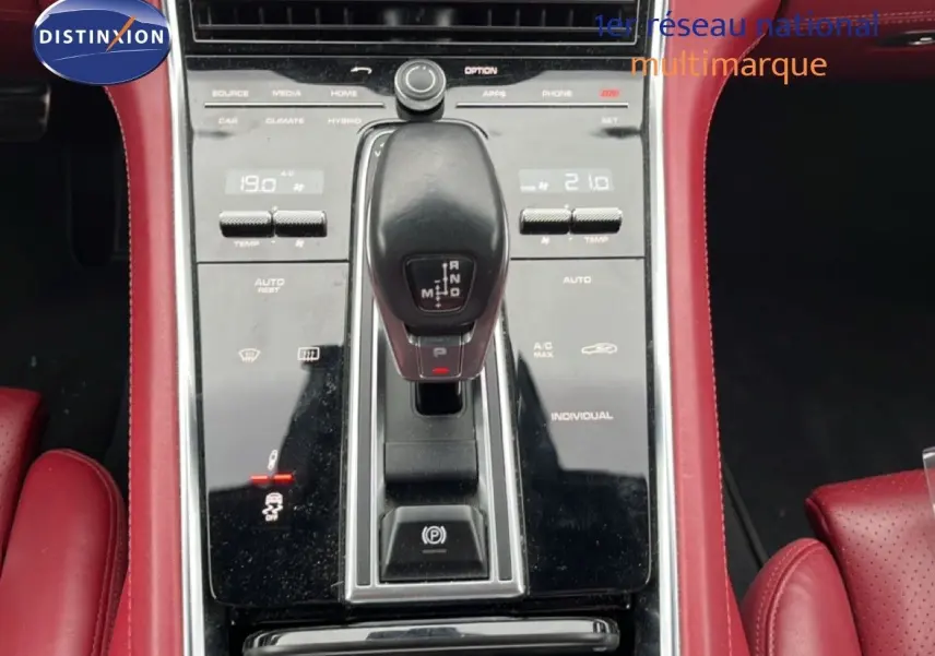 Vue rapprochée de la console centrale noire et levier de vitesse d’une Porsche Panamera 4 E-Hybrid avec sellerie cuir rouge.