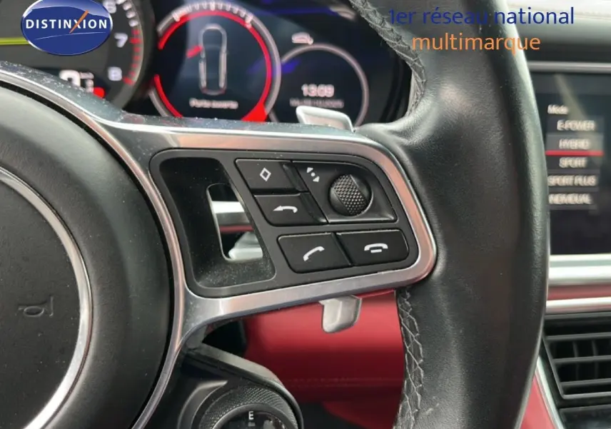 Gros plan sur le volant multifonction en cuir noir de la Porsche Panamera 4 E-Hybrid avec tableau de bord numérique rouge.