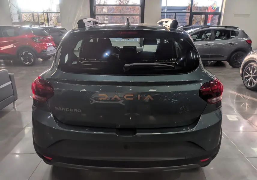 Vue arrière d'une Dacia Sandero Stepway 2025 en vert cèdre, avec logo DACIA en relief cuivré visible.