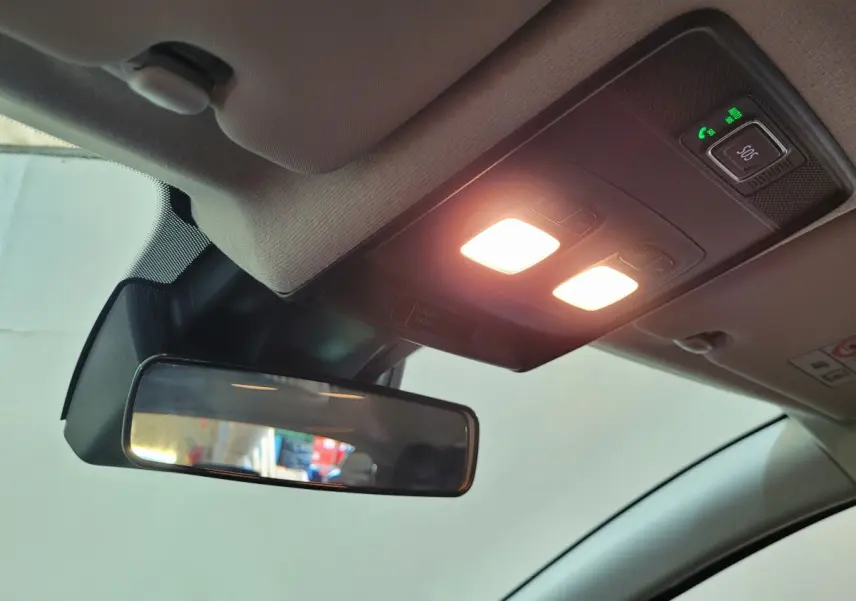 Vue intérieure du plafonnier et du rétroviseur central de la Renault Clio gris foncé avec éclairage activé et bouton SOS.