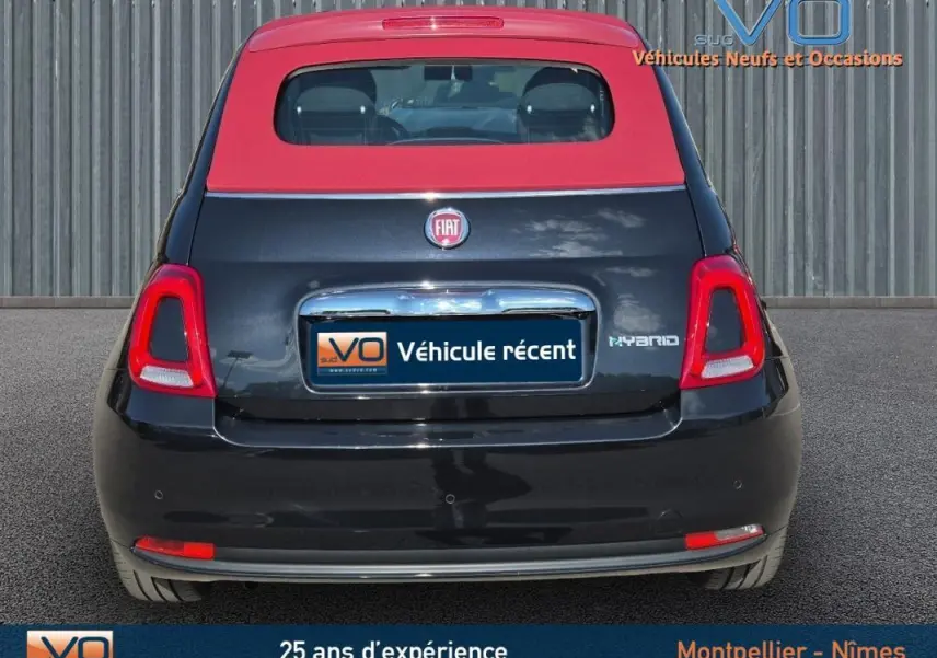 Vue arrière d'une FIAT 500C noire avec toit rouge, version hybride 2024, affichant le logo et l'inscription Hybrid.