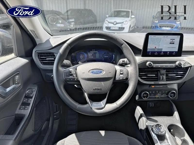 Vue intérieure centrée sur le volant cuir multifonction du Ford Kuga 2022 avec écran tactile et commandes au tableau de bord.