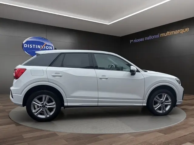 Vue 3/4 arrière droite d'un Audi Q2 blanc 30 TDI 116 Design avec feux arrière LED et jantes alliage.