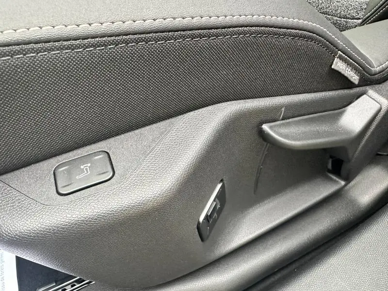 Gros plan sur la commande de réglage de siège côté gauche, tissu noir et plastique gris foncé à l'intérieur du Peugeot 3008 2025.