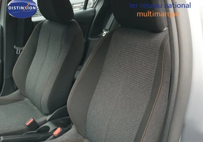 Gros plan sur les sièges avant en tissu noir avec surpiqûres orange d'une Peugeot 208 gris Artense, vue côté droit.