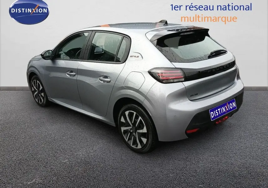 Vue 3/4 arrière droite d'une Peugeot 208 gris Artense métal avec jantes alliage et badge Style sur l'aile arrière.