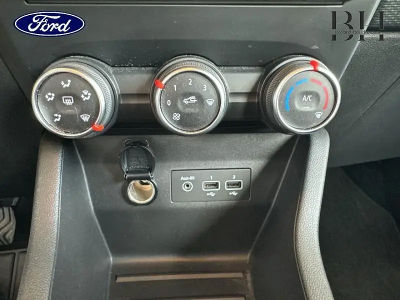 Vue rapprochée des commandes de climatisation et des ports USB sur le tableau de bord noir d'une Renault Clio gris platine.