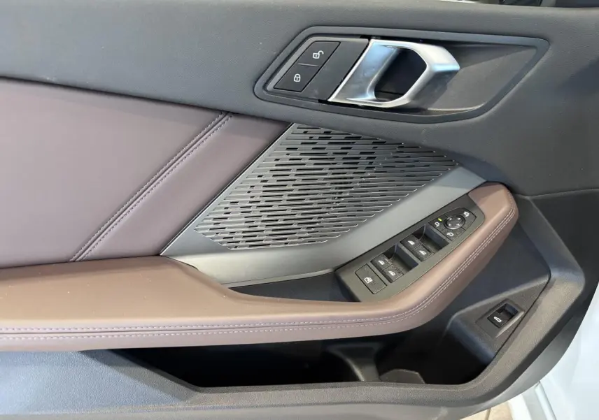 Détail de la porte côté conducteur de la BMW Série 1 120d M Sport 2025 blanche, avec commandes et garniture marron.
