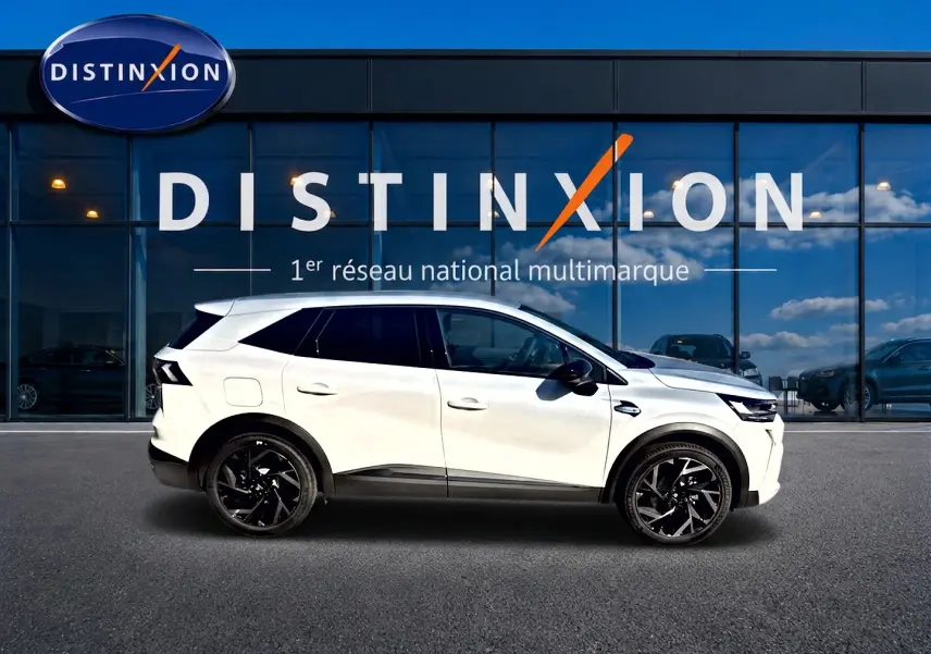 Profil droit du Renault Symbioz blanc nacré 2026 avec jantes noires et toit surélevé devant une vitrine Distinxion.