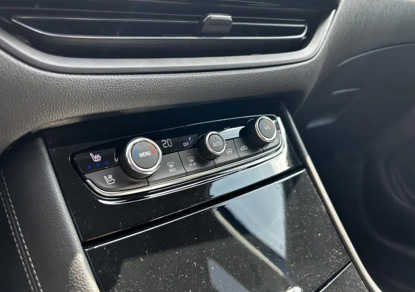 Gros plan sur la console centrale noire brillante avec commandes de climatisation de l'Opel Grandland 1.6 Hybrid 2022.