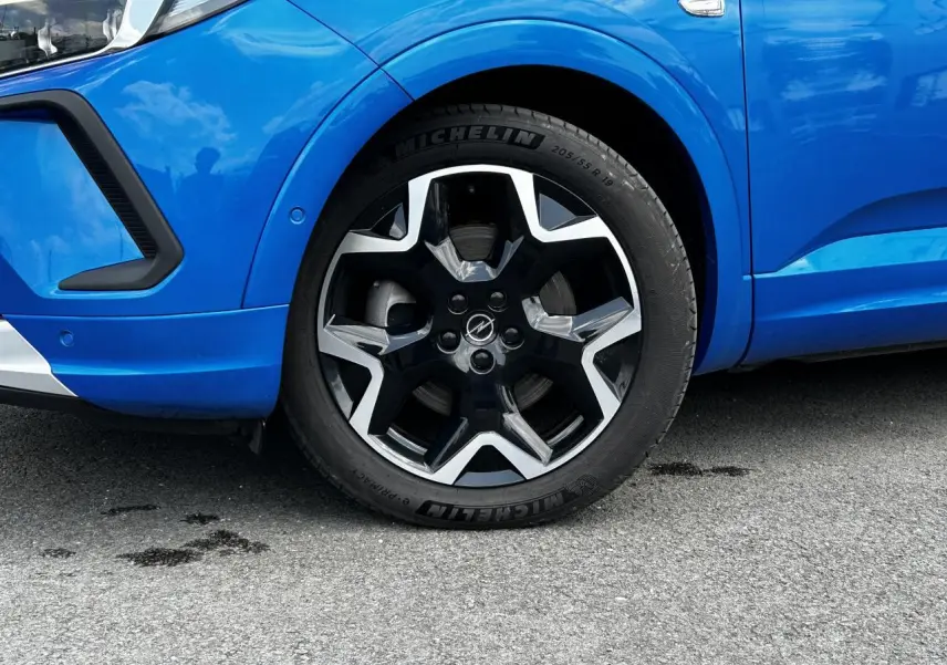 Gros plan sur la roue avant gauche de l'Opel Grandland bleu Vertigo avec jante alliage noire et argentée distinctive.