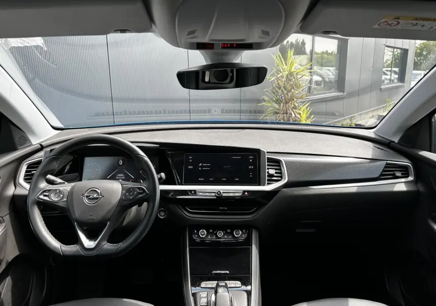 Vue intérieure avant de l'Opel Grandland bleu Vertigo, tableau de bord moderne avec écran tactile et volant cuir multifonction.