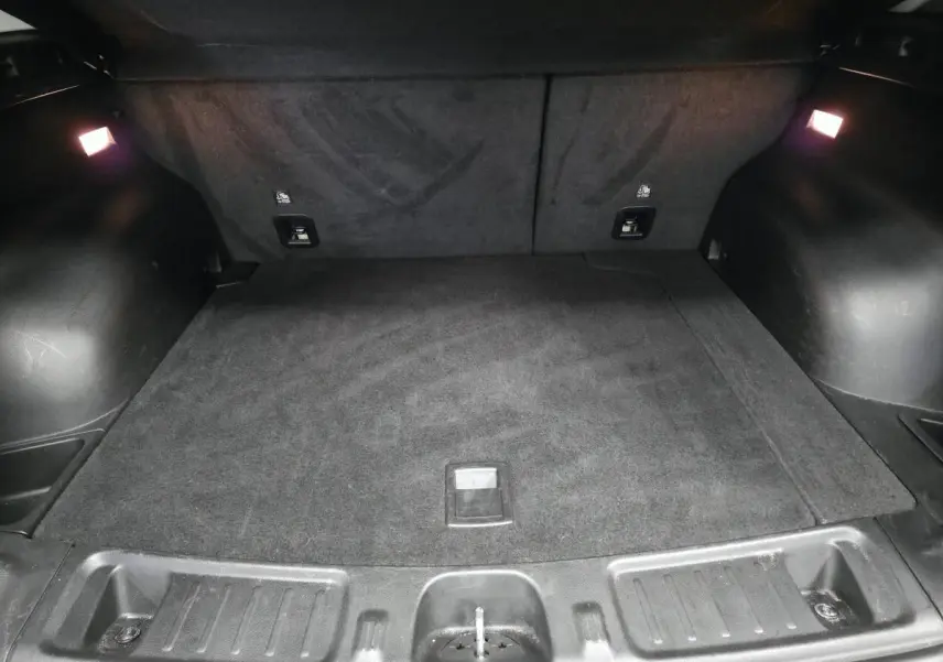 Coffre spacieux et noir du Jeep Compass 2024 hybride rechargeable, éclairé par deux lampes intérieures.