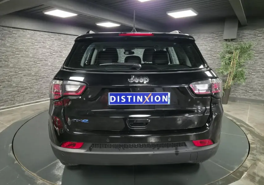Vue arrière d'un Jeep Compass noir 2024 avec logo eAWD et plaque Distinxion dans un showroom moderne.