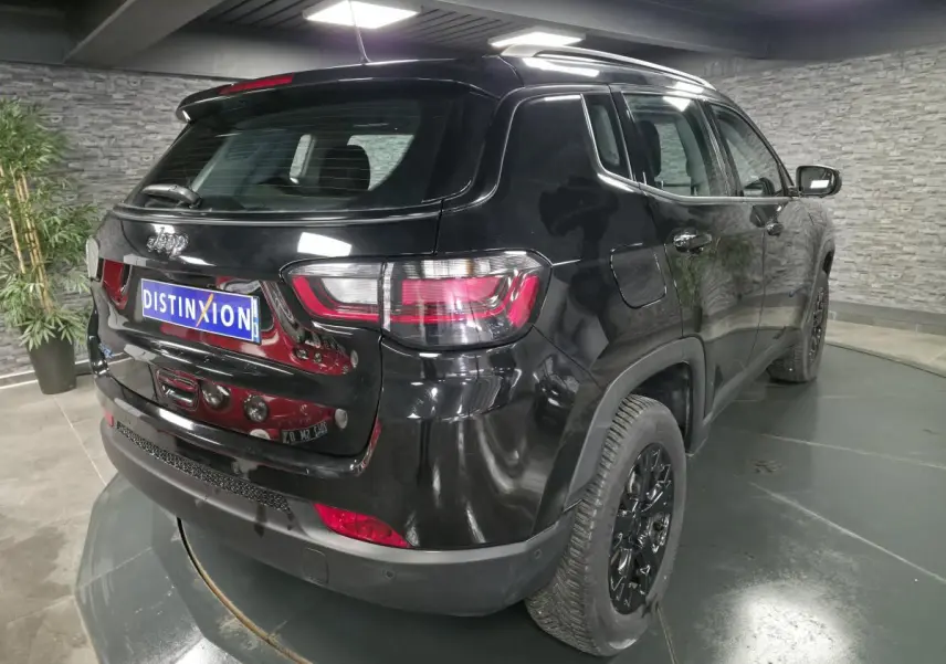 Vue 3/4 arrière droite d'un Jeep Compass noir avec jantes noires et feux arrière LED dans un showroom.