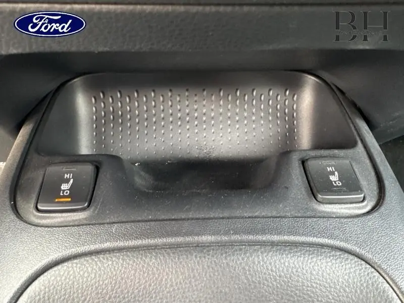 Gros plan sur les commandes de sièges chauffants en position haute, dans l’habitacle noir d’une Toyota Corolla gris Manhattan.