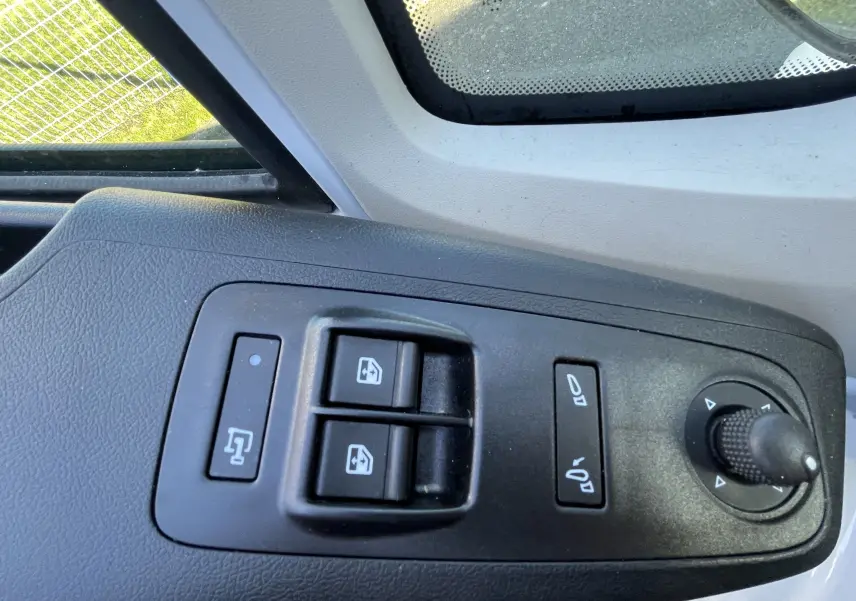 Gros plan sur les commandes de lève-vitres et réglage des rétroviseurs côté conducteur du Peugeot Boxer Fourgon blanc.