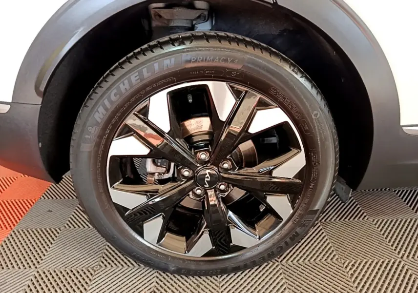Gros plan sur la roue avant droite du KIA SPORTAGE blanc, jante alliage noir brillant avec pneus Michelin.