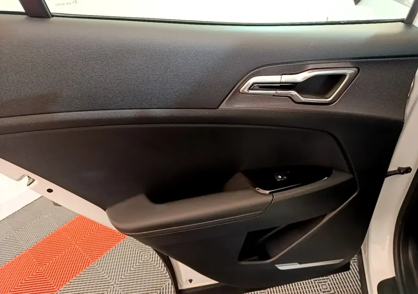 Vue intérieure de la porte avant droite noire avec poignée argentée du Kia Sportage blanc 2022 hybride rechargeable.